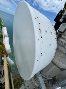 A large white industrial tank with bolts and a green pipe attached.
